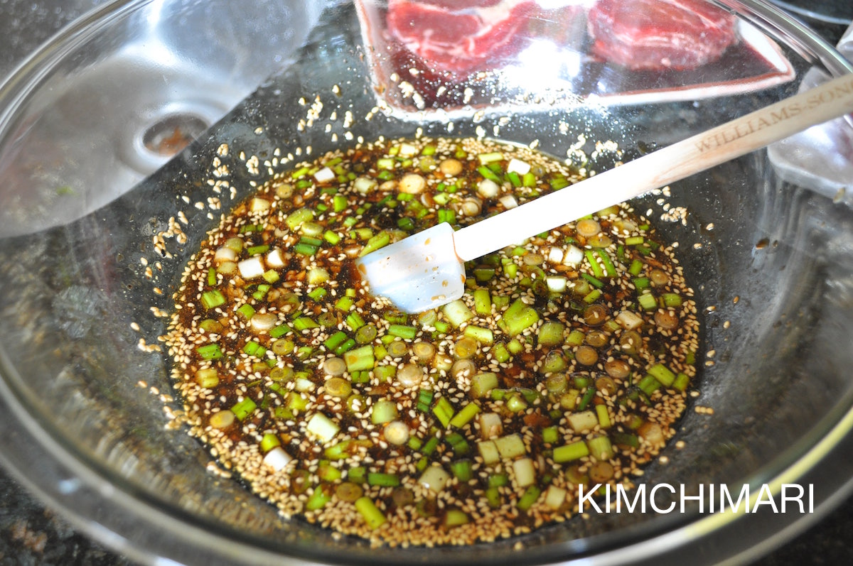 Marinade with soy sauce, green onions and other seasonings in glass bowl