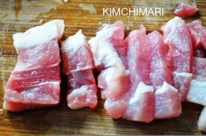 cut pork belly pieces on cutting board for kimchi jjigae