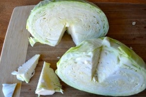 Half cut cabbage with core cut out on cutting board