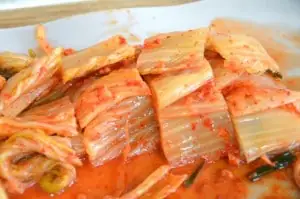Cabbage Kimchi cut into slices on cutting board