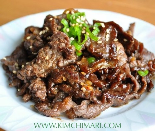 Bulgogi cooked and plated, garnished with chopped green onions on top