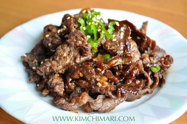 Bulgogi cooked and plated, garnished with chopped green onions on top