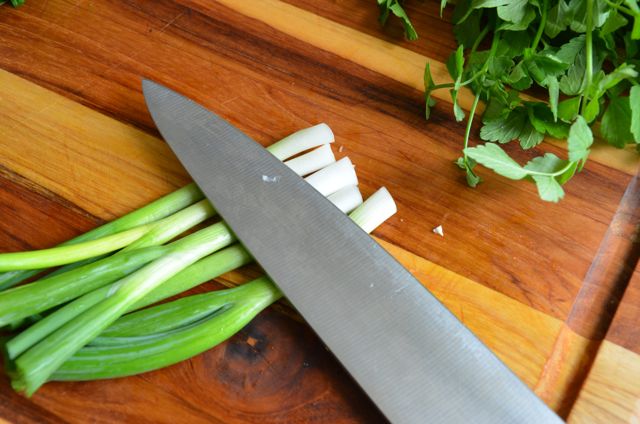 Smashing white part of green onions with side of knife