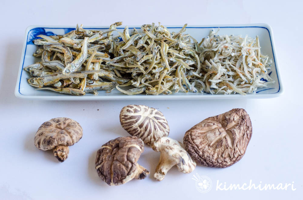 small and large korean dried anchovies and dried shitake mushrooms on white background