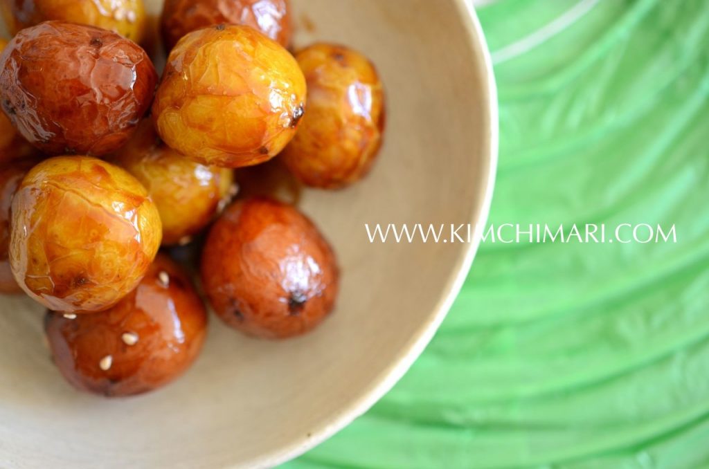 Soy sauce glazed shiny baby potatoes in a bowl on green paper background