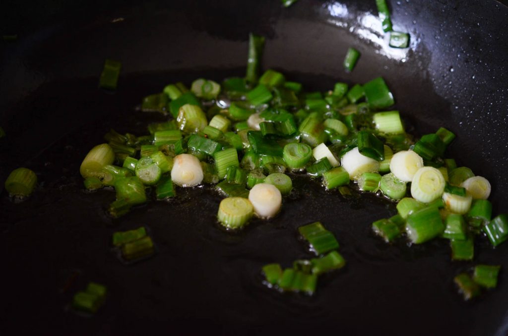 Green onions sauteeing in oil for spicy squid stir fry