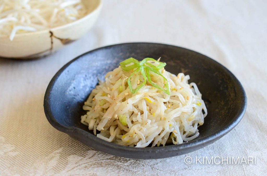 Bean sprouts side dish in black bowl topped with green onions