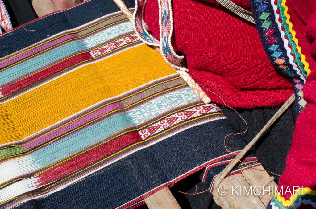 Peru woman weaving traditional textile from alpaca yarn