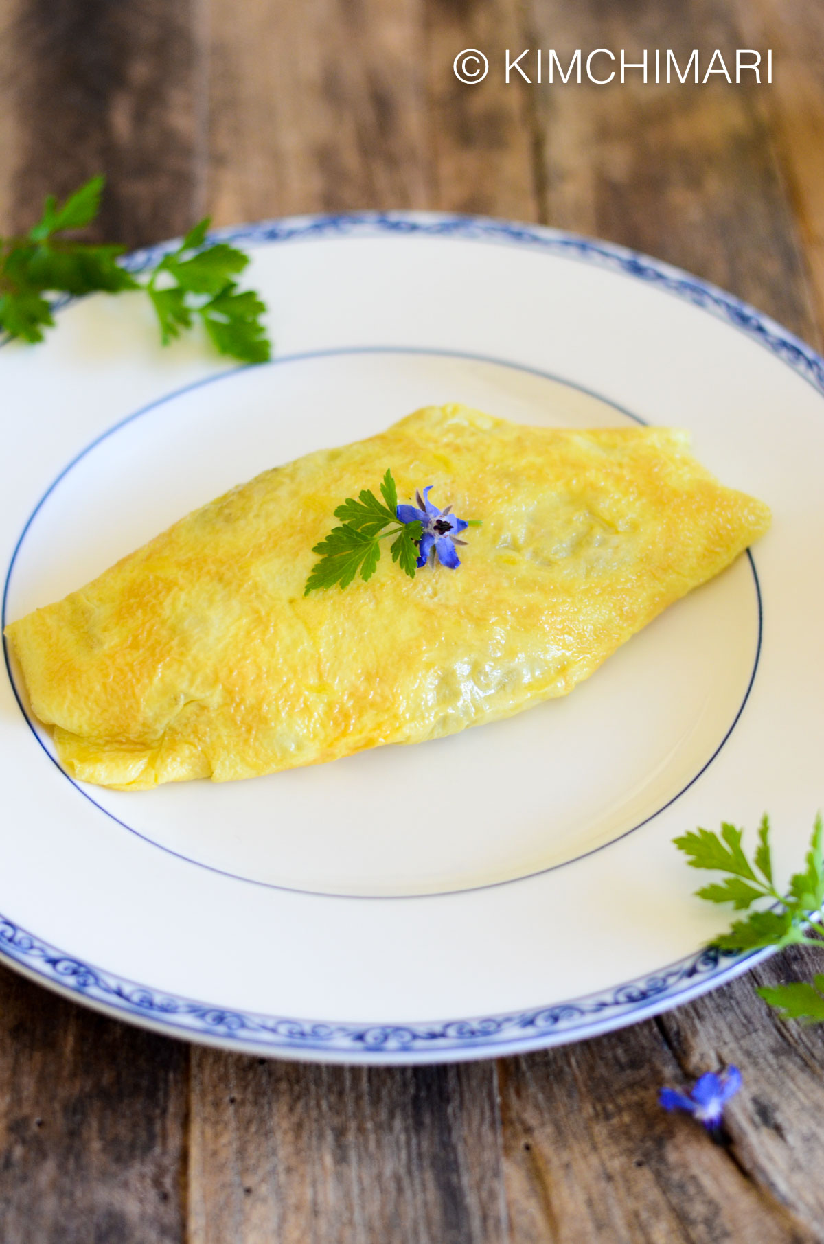 omurice served on white plate garnished with parsely and boroage blossoms