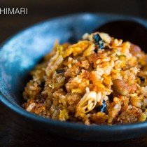 Kimchi Fried Rice in black bowl with wooden spoon