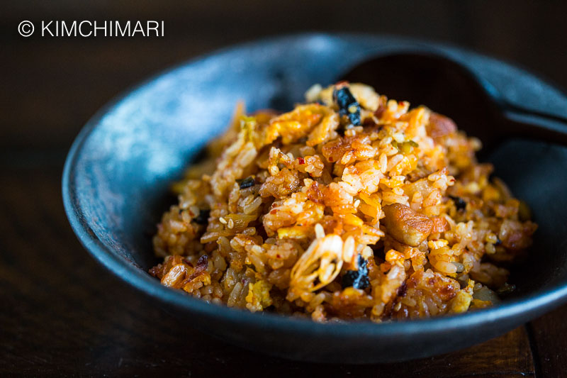 Kimchi Fried Rice in black bowl with wooden spoon