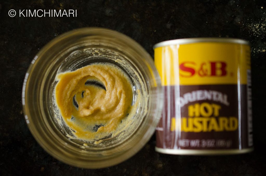 Yellow Mustard paste in bowl next to S&B Hot Mustard Powder can