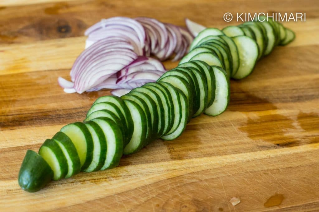 Japanese cucumber and red onions sliced on cutting board