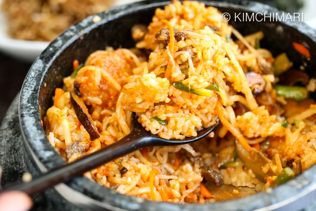 A spoonful of Bibimbap in stone pot all mixed with gochujang
