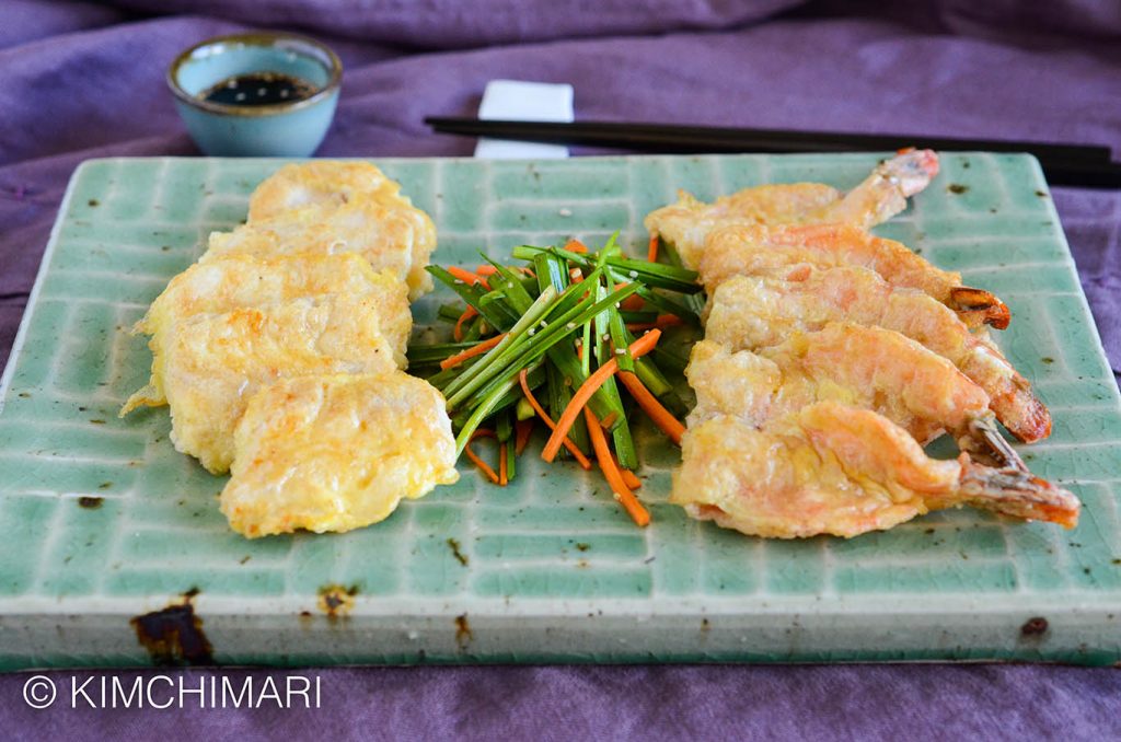 fish and shrimp jeon plated on green rectangular plate with chive salad in center