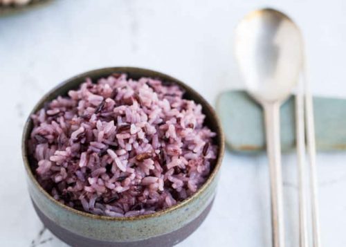 Korean purple rice in bowl with silver spoon and chopsticks