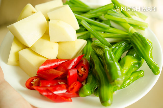 Cut potatoes, green onions, chili peppers on plate