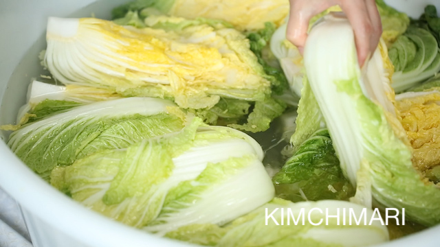 Turning over cabbages in brine after 3 hours of pickling for Kimchi