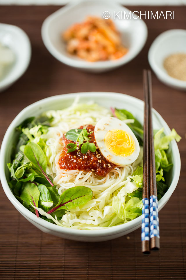 Finished pic of bibim guksu with all toppings and gochujang bibim sauce with chopsticks on bowl