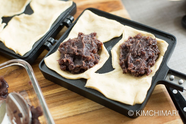 one side of Bungeoppang pan covered in dough sheet then filled with sweet red bean paste