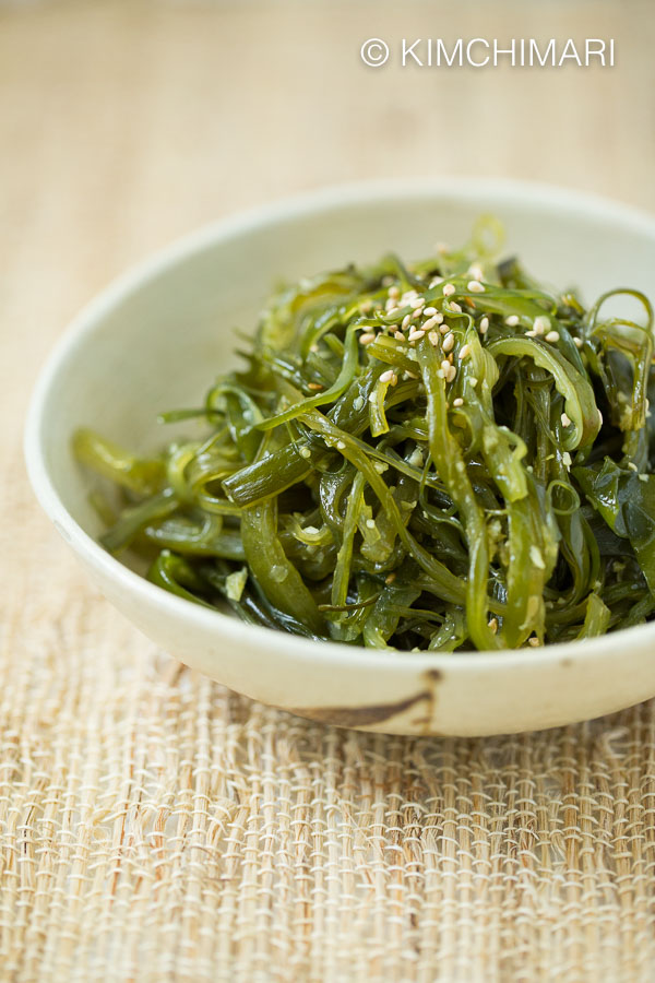 Cooked Seaweed side dish plated on light cream colored shallow dish, sprinkled with sesame seeds