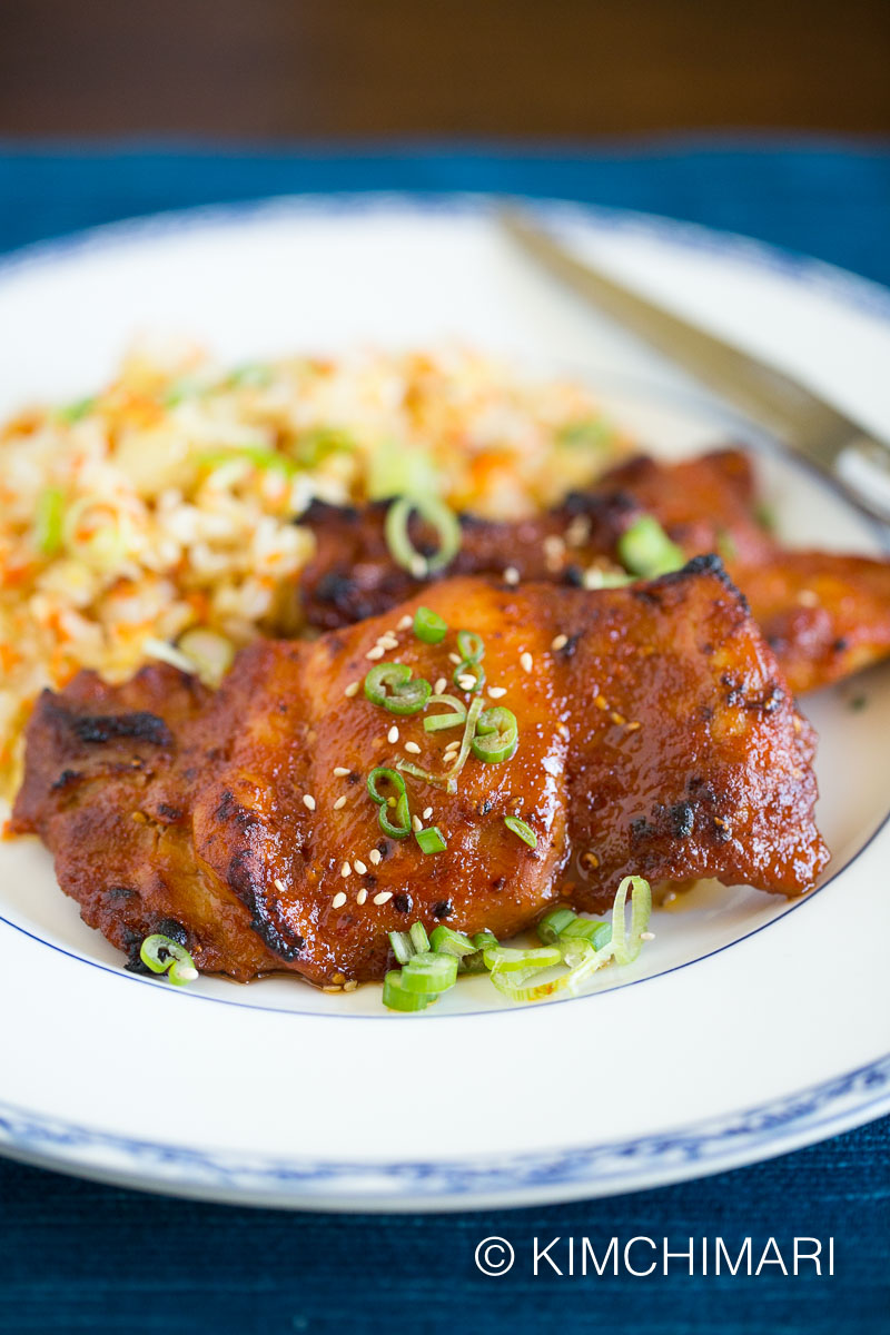 baked spicy chicken thighs plated with simple carrot fried rice