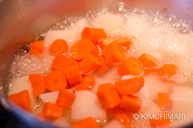 Carrots added to potatoes in pot