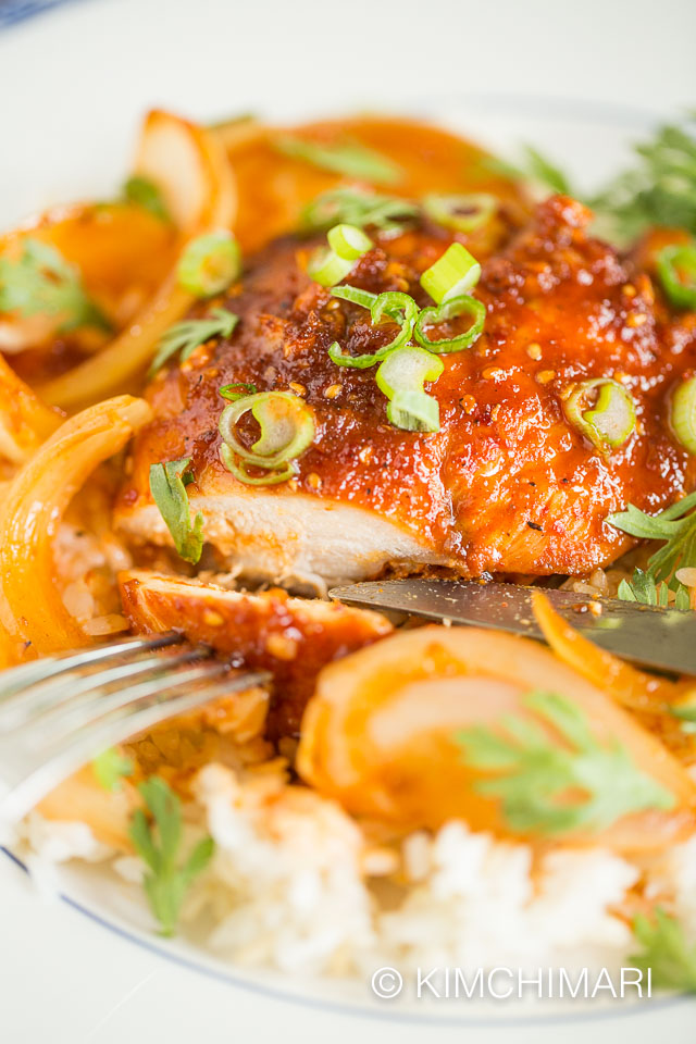 chicken breast sliced and served on top of rice on white plate