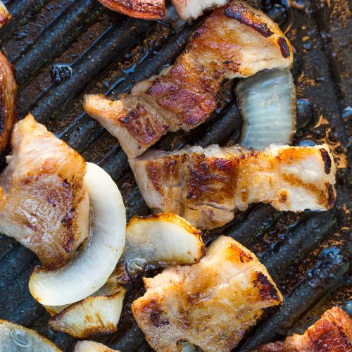 pork belly pieces and onions grilling on korean grill pan