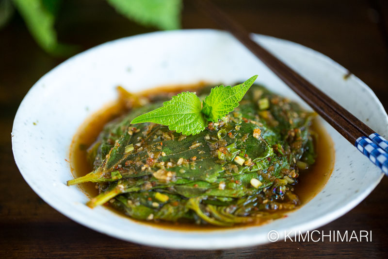 steamed perilla leaves plated on white dish with chopsticks
