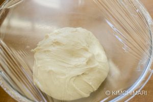 dough in bowl covered with plastic wrap to be proved