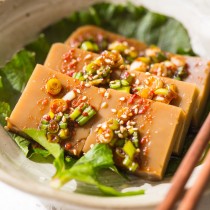 Acorn Jelly pieces laid out on plate on greens then topped with sauce
