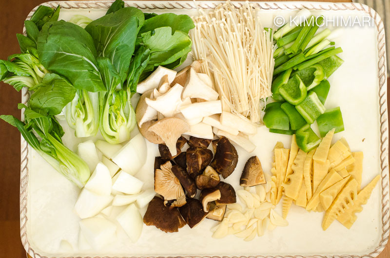 cut bok choy, mushrooms, bell pepper, onion, bamboo shoots, garlic, green onions on tray