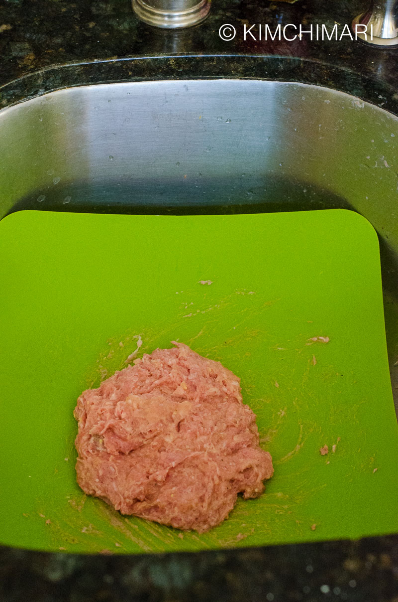 meatball mixture thrown on the plastic cutting board inside sink