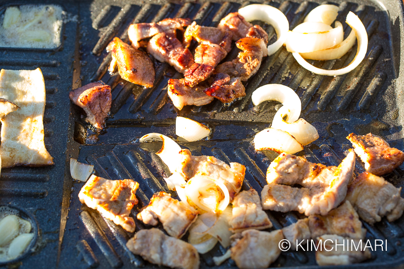 pork belly and onion pieces grilling on the pan