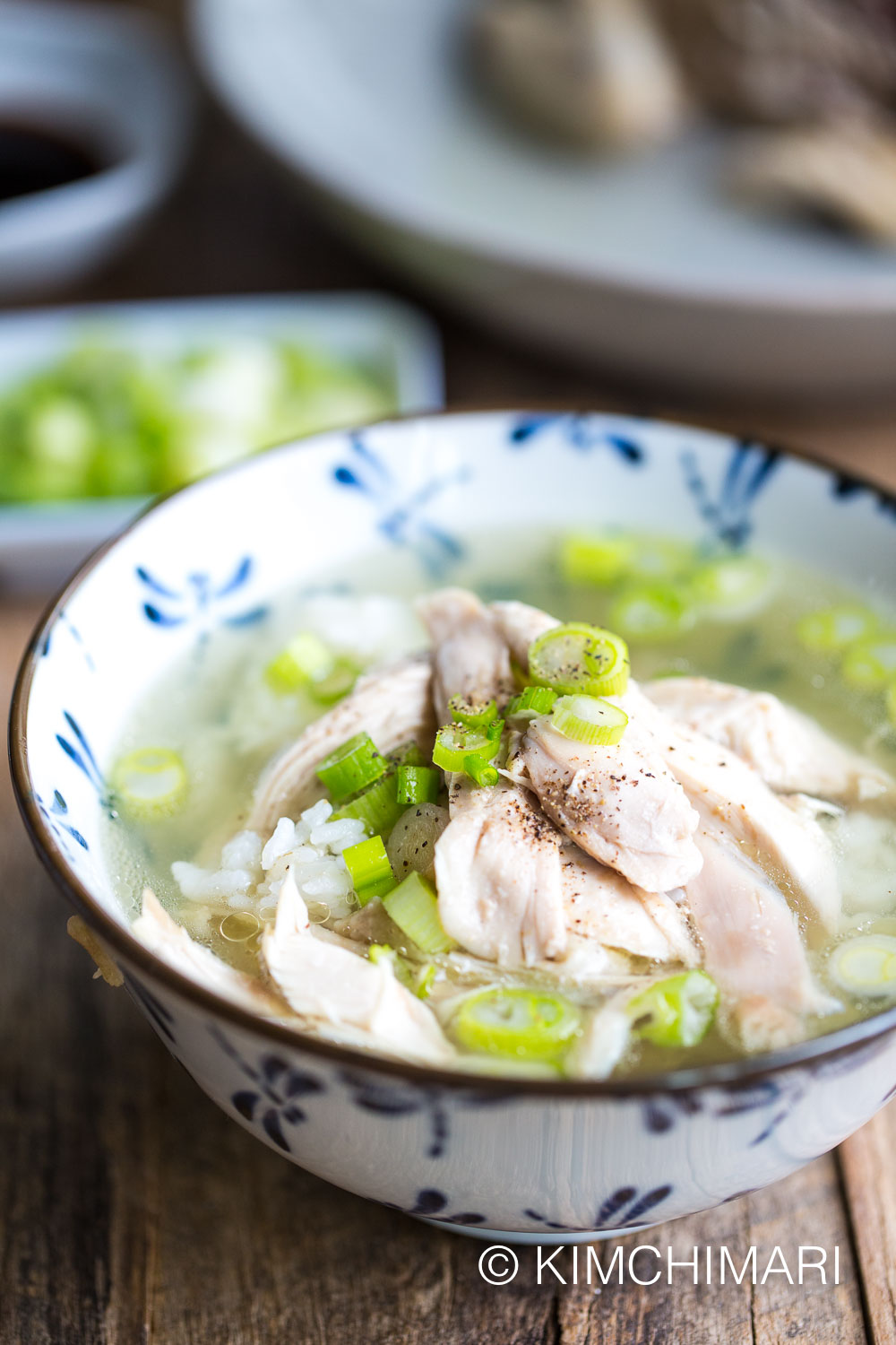 korean chicken soup in bowl with rice, soup and torn meat on top with chopped green onions
