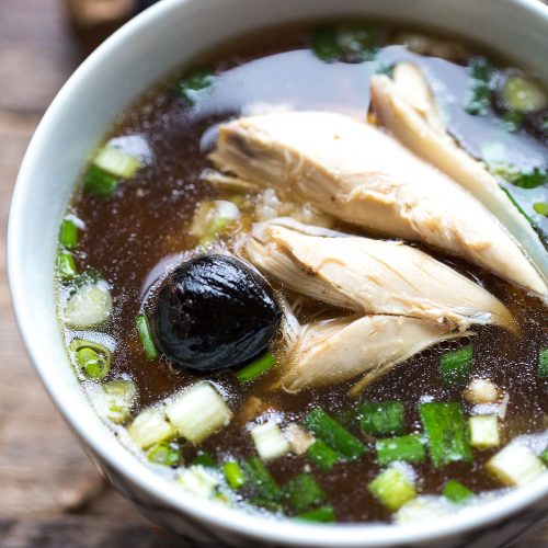 Korean Chicken soup with torn meats in bowl with Black Garlic and green onions