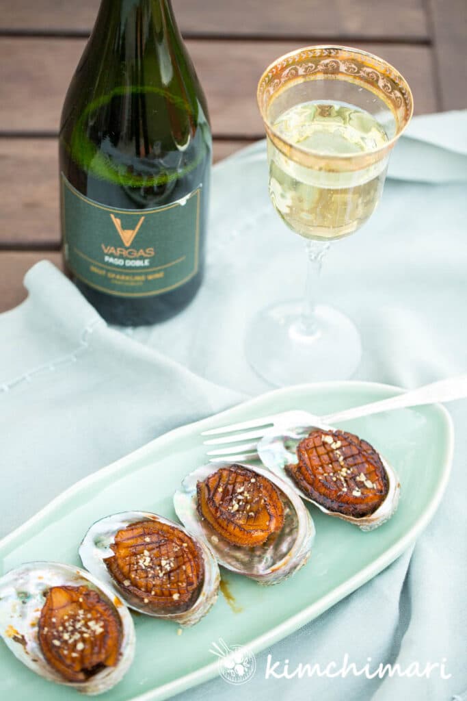 korean pan fried abalone plated with a bottle of champagne and glass