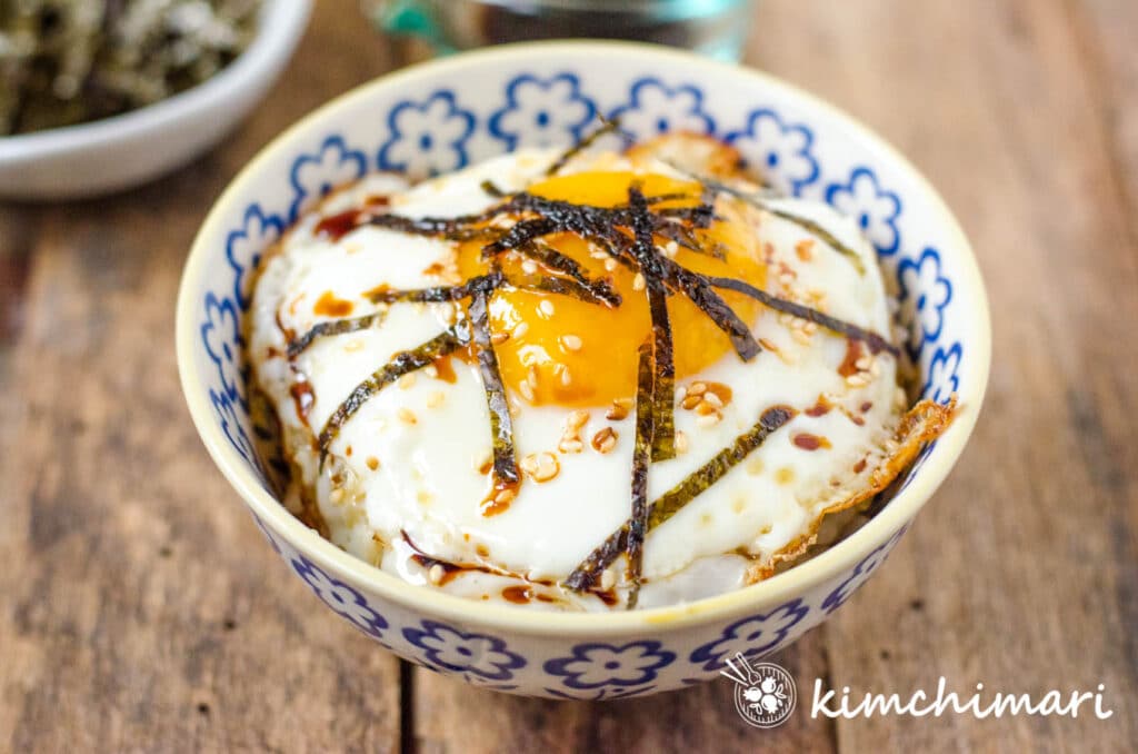 bowl of rice topped with fried egg with bits of seaweed