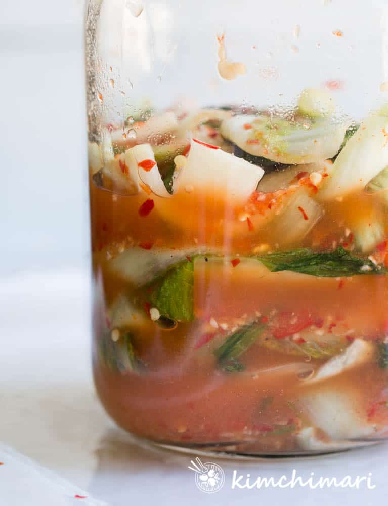 side view of cabbage kimchi inside a glass jar