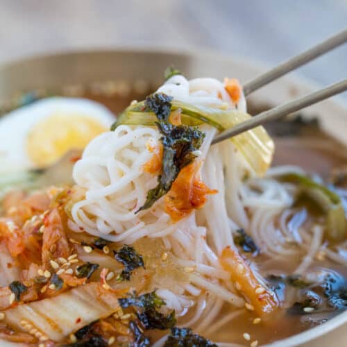 Kimchi Cold noodle soup noodles picked up with chopsticks