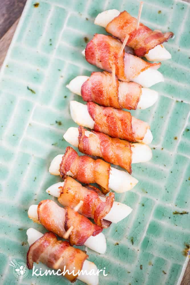 bacon tteok gui lined on green ceramic plate with toothpicks