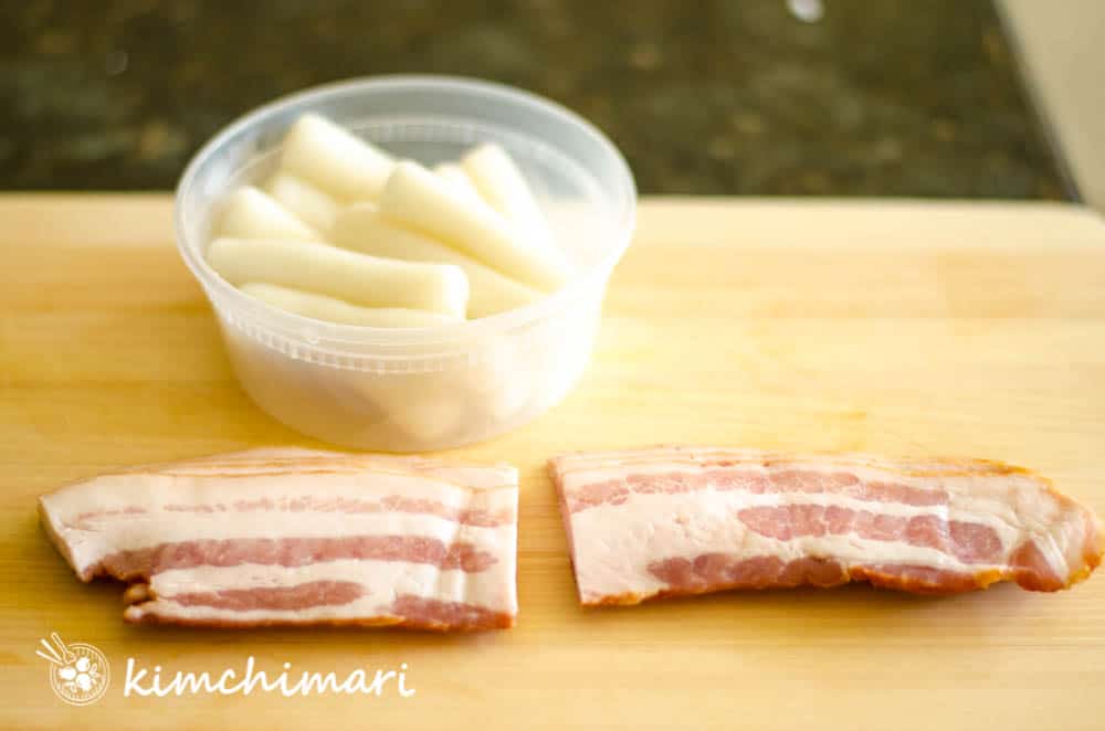 bacon slices and tteok on cutting board