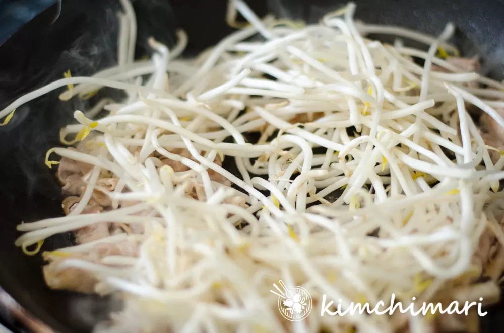 bean sprouts added to pork belly stir fry in pan