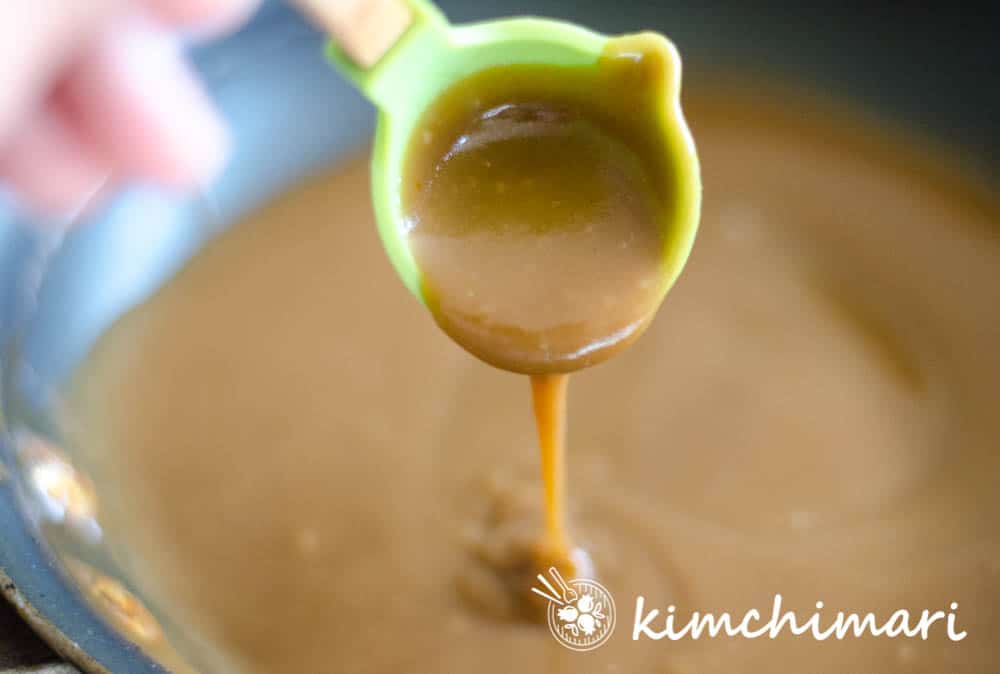 brown sauce being poured out from a ladle