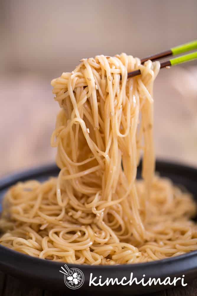 soy sauce bibim guksu noodles picked up with chopsticks