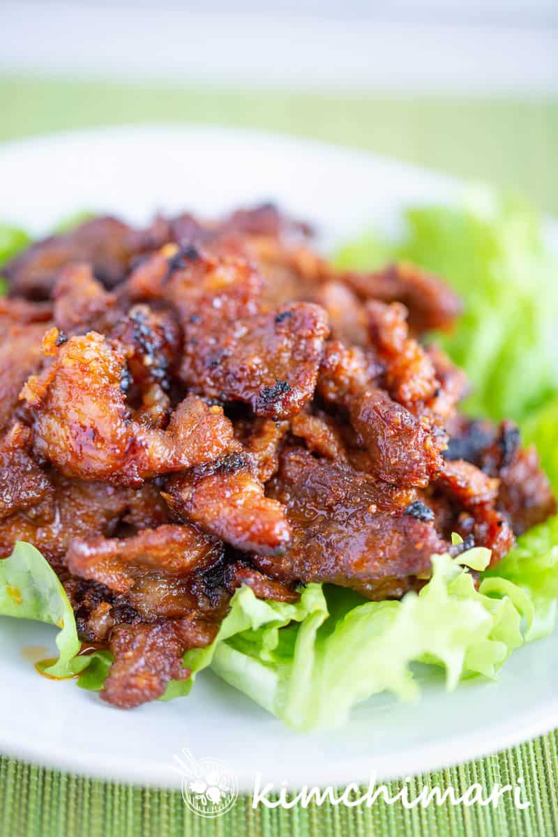 oven baked korean spicy pork on green lettuce lined plate