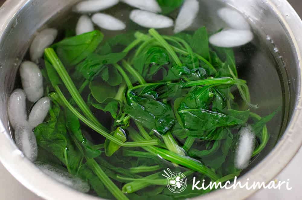 blanched spinach in bowl of ice water