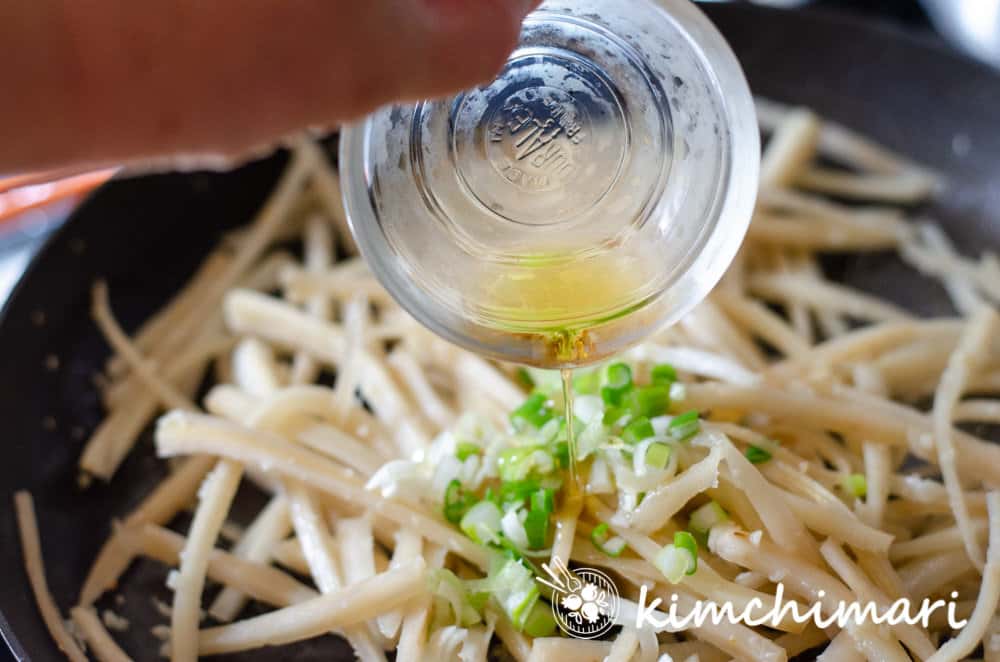 sesame oil being added to pan with bellflower roots