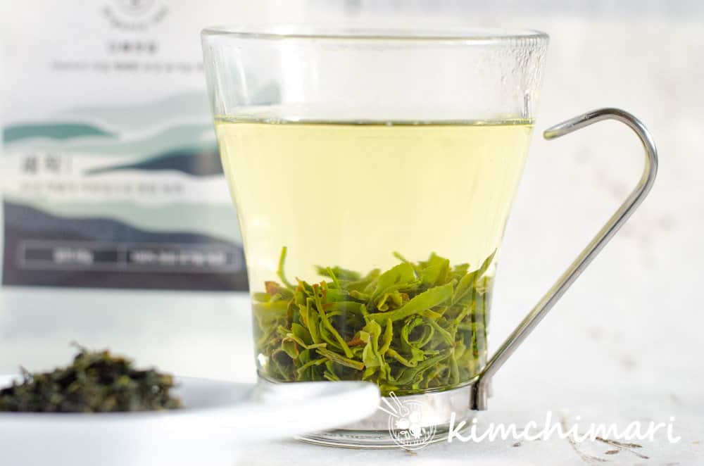 korean green tea leaves brewing in glass cup